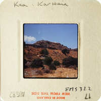 Mountainous landscape with sparse vegetation, captured on an old photograph.