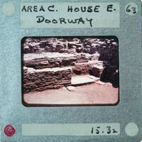 Excavated stone walls with a doorway on right.