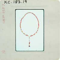 A vintage image of a bead necklace with a tassel on an old postcard.