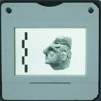 Small stone sculpture of a face displayed on a screen with measurement lines.