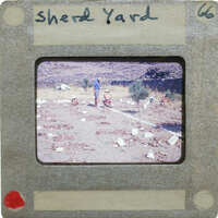 A slide of a yard with people, trees, and piles of pottery.