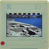 A plastic film strip viewer displaying a photograph of ancient ruins by the water.