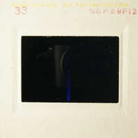 This is an image of a film strip with a black frame, showing a dark scene and a blue light.