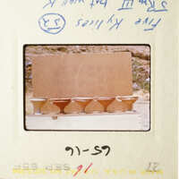 The image shows a collection of small cups on a table, with a handwritten note above them.