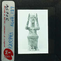 A photograph of an ancient sculpture, possibly a figurine or statue, with a label and stamp indicating it is from the Cincinnati Art Museum.