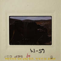 A photograph showing an old stone structure with mountains in the background, on a film strip labeled "HS-59".