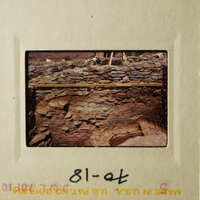 This is an image of a rock wall with a wooden structure on top, possibly indicating an archaeological site.