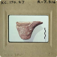 Ancient ceramic artifact displayed on a white surface with measurement marks.