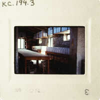 The photograph shows an empty room with long tables and benches, taken from a low angle.