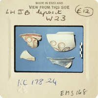 A collection of broken pottery pieces on display with labels and information.