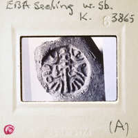 A photograph of a stone with an intricate design, possibly a religious symbol, encased in a protective display case.