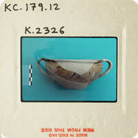 Ancient Greek-style ceramic cup with intricate designs, displayed on a blue surface.