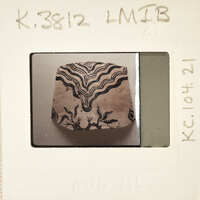 A small, intricately carved wooden object with a decorative pattern on it.