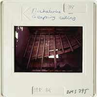 Old photo of an attic with exposed wooden beams and damaged ceiling.