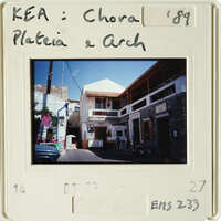A photograph of an old European village with white walls and brown roofs, taken from a balcony.