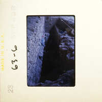 A dark, narrow tunnel with debris and an opening at the end.