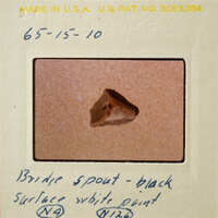 A small brown object on a white surface, possibly a bridge spout.