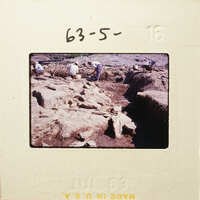 People working on an archaeological site with excavated earth and rocks.