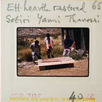 Three men working on a clay structure outdoors.