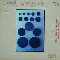 A collection of blue lead weights on a white surface with labels and numbers.