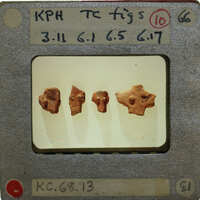 Four small clay figurines on a display stand with labels.