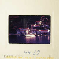 A colorful photo of a scenic coastal village with boats and houses by the water.