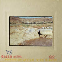 This is an image of two polaroid photos placed side by side, showing a rocky riverbank and a barren landscape with a distant building.