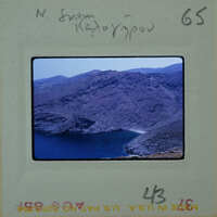 A photograph of a mountainous landscape with a body of water, enclosed within an old-fashioned film strip border.