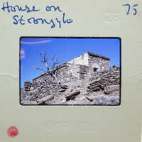 Old stone building on a rocky hillside with blue sky.