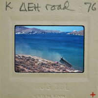 A photograph of a coastal landscape with a boat and mountains, taken on July 7th, 1976.