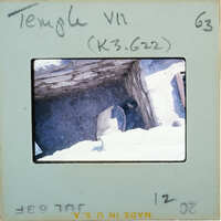 Broken base of terracotta figurine skirt on dirt floor surrounded by stone walls.