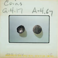 Two coins on a label with handwritten numbers and letters.