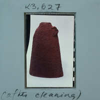 A photograph of a red artifact, possibly an ancient pottery piece, with cleaning instructions written on it.