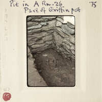 The image is a vintage photograph of an underground cave with stone walls and a small, dark opening at the bottom.