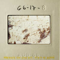 A vintage photograph of an outdoor scene with a pile of rocks and dirt, featuring handwritten notes on the border.