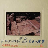 Two photographs showing an archaeological site with stone ruins, taken from different angles and featuring a brick wall and rocky terrain.
