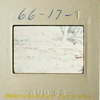 An image showing a vintage photograph with a handwritten note, depicting an outdoor scene with a person and a rocky landscape.