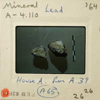 Two small rocks on a white surface with measurement lines and labels, including "Minerals" and "Lead".