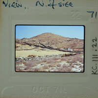 A photograph of a desert landscape with a rocky hill and stone walls.