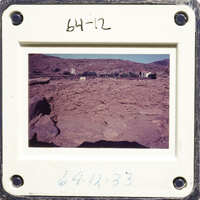 A photograph of an outdoor dirt area with rocky terrain and sparse vegetation.