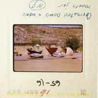 A photograph of a wooden table with various items on it, including a cup and a bowl, set against a backdrop of a rural landscape.