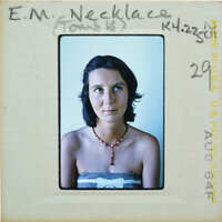 A vintage passport photo of a woman wearing a necklace and looking away from the camera.