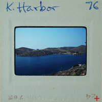 A vintage photograph of a serene harbor with calm waters and distant hills.