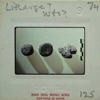 Image of three small, round objects on a white surface with shadows cast by them.