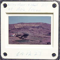 A photograph of a mountainous landscape with terraced fields and houses, taken from an elevated perspective.