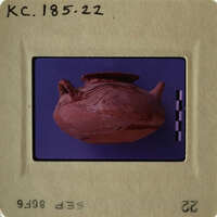 Ancient clay pot with handle and spout, photographed on a purple background.