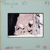 Stone walls around floor with broken pots.