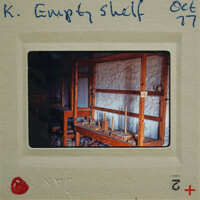 A photograph of an empty wooden shelf with a label on the front.