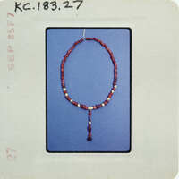 A string of red beads with a tassel hanging from it.