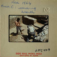 Two men working on stone ruins, possibly archaeologists or construction workers.